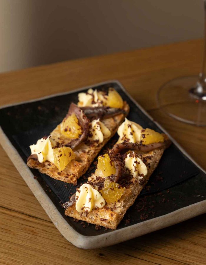 Tostas de anchoa con mantequilla, naranja y polvo de aceituna negra (2 ud.)
| 9€